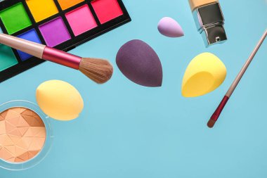 Renk arkaplanında uçan makyaj aksesuarları ve kozmetik ürünleri