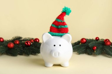 Bej arka planda Noel şapkası ve dekoru olan domuz kumbarası