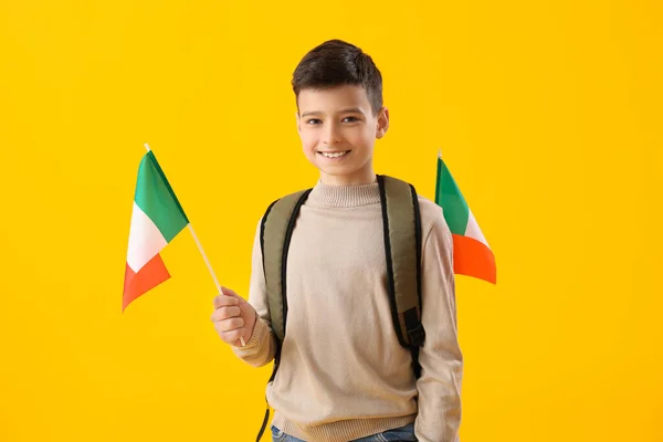 Little boy with backpack and flags of Italy on yellow background
