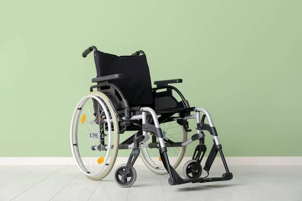 stock image Modern empty wheelchair near green wall