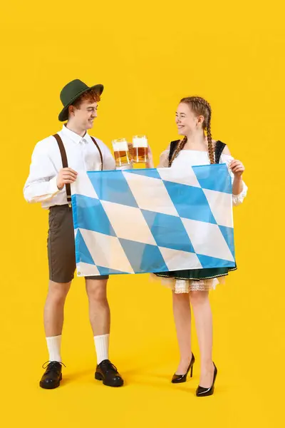 Mladý Pár Tradičním Německém Oblečení Pivem Bavorskou Vlajkou Žlutém Pozadí — Stock fotografie