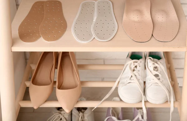 Shoe rack with stylish shoes and orthopedic insoles, closeup