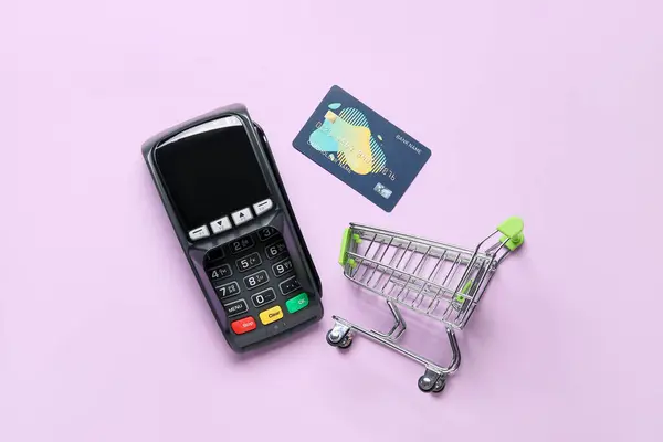 带有支付终端和紫色背景信用卡的购物车 — 图库照片
