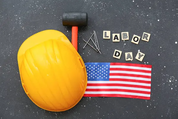 Hardhat, rubber mallet, USA flag and text LABOR DAY on grey grunge background