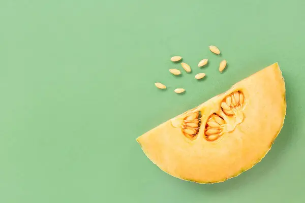 Piece of sweet melon and seeds on green background