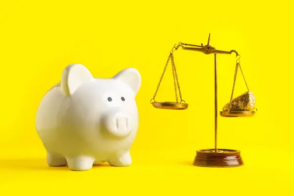 Piggy bank with scales of justice on yellow background