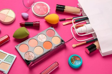 Pembe arka planda makyaj malzemesi olan alışveriş çantası, yakın plan.