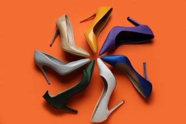 Turuncu arka planda farklı yüksek topuklu ayakkabılar.