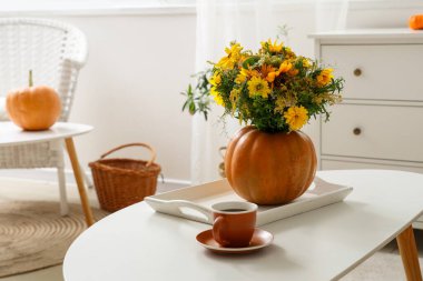 Sonbahar çiçekli balkabağı ve oturma odasındaki masada bir fincan kahve.