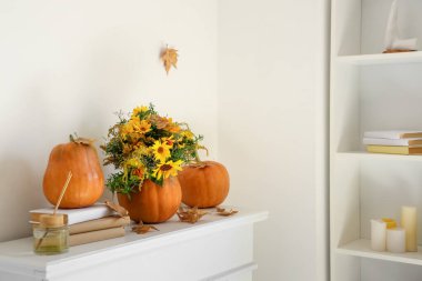 Çiçekli balkabakları, düşmüş yaprakları ve şömine rafındaki kitapları.