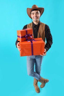 Cadılar Bayramı için giyinmiş genç adam mavi arka planda hediyeleri olan bir kovboy gibi.