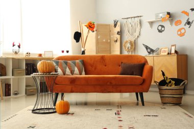 Cadılar Bayramı için kırmızı kanepe ve balkabaklarıyla dekore edilmiş oturma odasının içi.