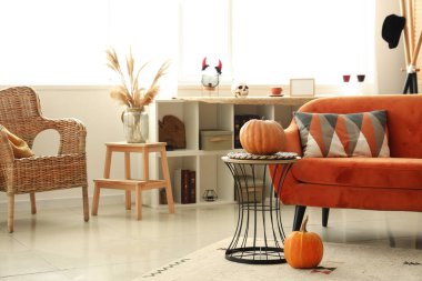 Cadılar Bayramı için kırmızı kanepe ve balkabaklarıyla dekore edilmiş oturma odasının içi.