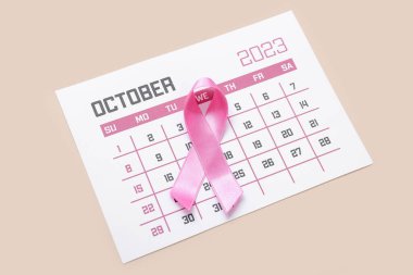 Bej arka planda takvimi olan pembe kurdele. Göğüs kanseri farkındalığı konsepti