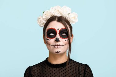 Cadılar Bayramı için mavi arka planda giyinmiş genç bir kadın, yakın plan.