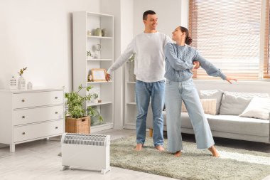 Genç çift radyatörün yanında dans ediyor.