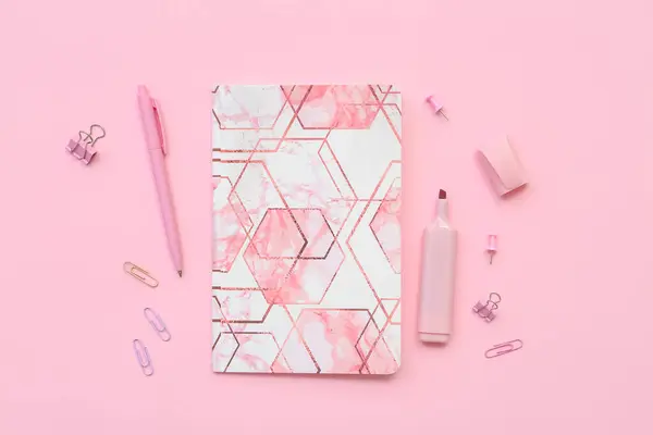 Composition with notebook, paper clips, pen and marker on pink background