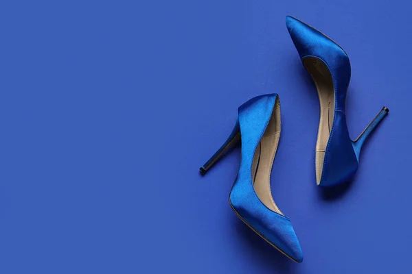 Stylish blue high heels on color background