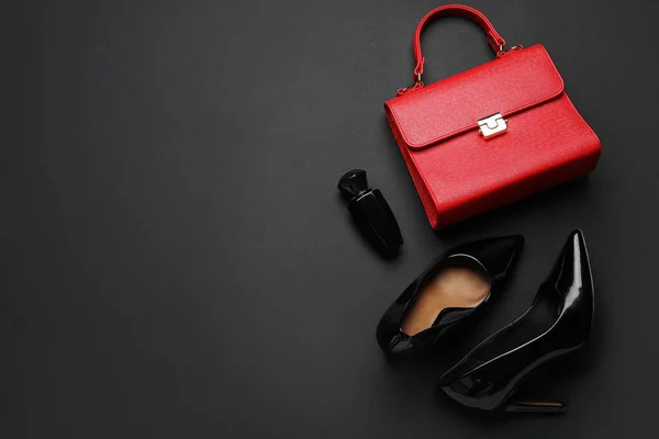 Stylish black high heels with handbag and perfume on color background