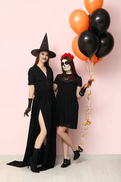 Fiatal Nők Öltözött Halloween Léggömbök Közelében Fény Fal — Stock Fotó