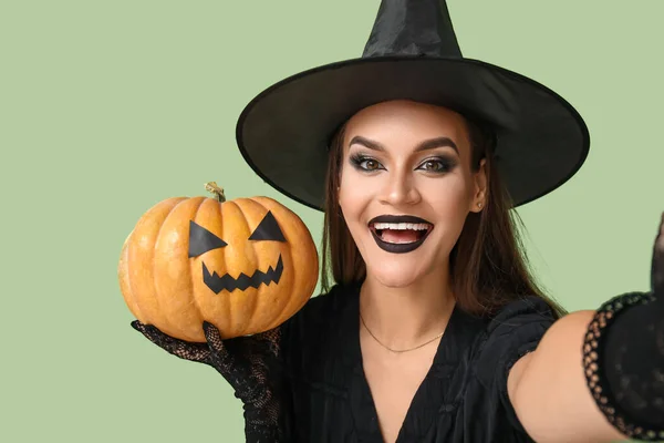 Молодая Женщина Одетая Хэллоуин Ведьма Тыквой Делающая Селфи Зеленом Фоне — стоковое фото