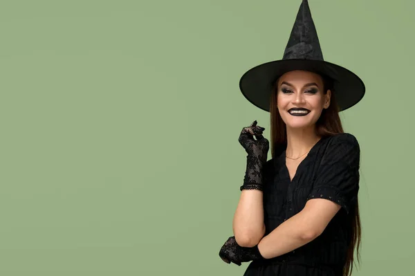 Młoda Kobieta Ubrana Halloween Jako Czarownica Zielonym Tle — Zdjęcie stockowe