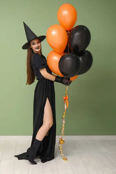 Fiatal Öltözött Halloween Boszorkány Léggömbök Közelében Zöld Fal — Stock Fotó
