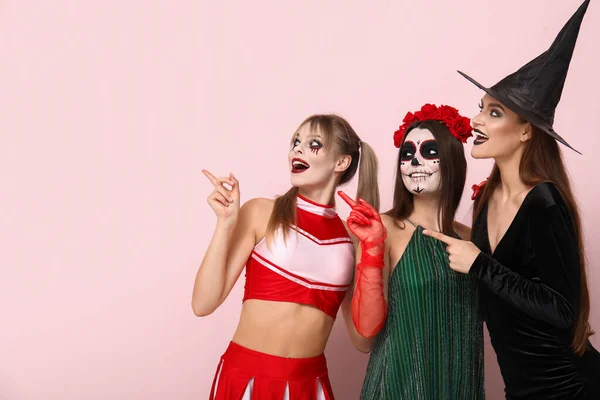 Amigos Femininos Vestidos Para Halloween Apontando Para Algo Fundo Rosa — Fotografia de Stock
