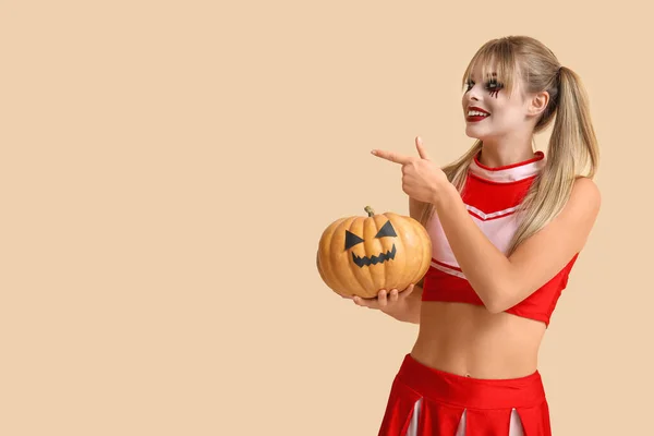 Mladá Žena Oblečená Halloween Jako Roztleskávačka Dýní Ukazuje Něco Béžovém — Stock fotografie