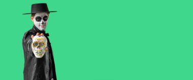 Yeşil arka planda kafatasını boyamış genç bir adam ve mesaj için yeri var. Meksika Ölüler Günü (El Dia de Muertos) 