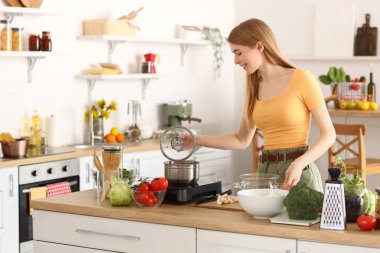 Genç bayan mutfakta makarna hazırlıyor.