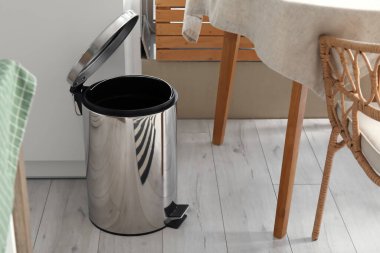 Modern mutfağın içindeki masanın yanındaki metal çöp tenekesi açıldı.