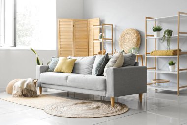 Işıl ışıl oturma odasının içinde yumuşak battaniyeli rahat gri kanepe ve sepet.