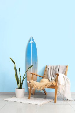 Oturma odasının içinde. Koltuğunda ekose ve sörf tahtası var.