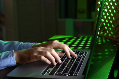 Kadın programcı gece ofiste dizüstü bilgisayarda daktilo kullanıyor.
