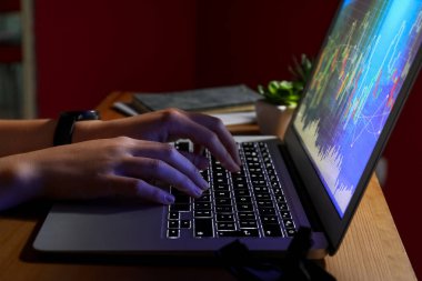 Kadın programcı gece ofiste dizüstü bilgisayarda daktilo kullanıyor.