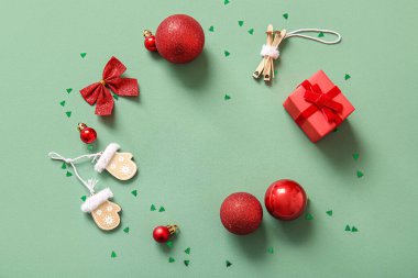 Yeşil arka planda Noel topları, konfeti ve hediye kutusundan yapılmış çerçeve