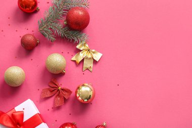 Topları, yayları ve pembe arka planda hediye kutusu olan Noel ağacı dalı