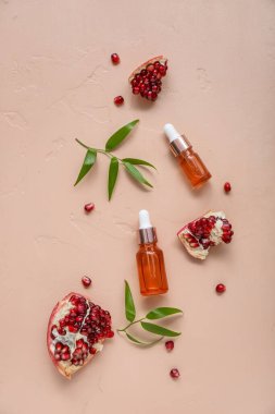 Gerekli yağ şişeleri, olgun nar ve renk arkaplanına bitki dalları ile bileşim