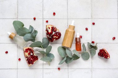 Temel yağ şişeleri, nar ve okaliptüs dalları hafif fayans zemin üzerinde bileşimi