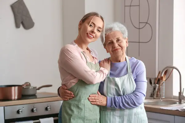 Young woman with her grandmother hugging in kitchen