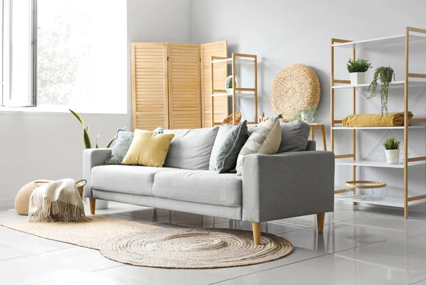 Işıl ışıl oturma odasının içinde yumuşak battaniyeli rahat gri kanepe ve sepet.