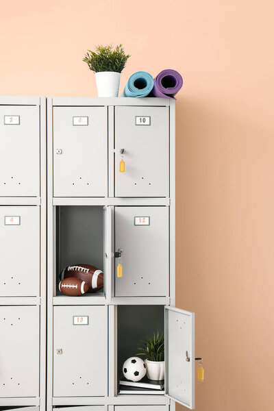 Modern locker with sports equipment near beige wall