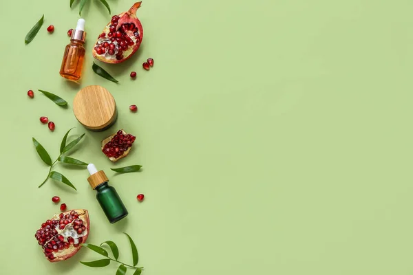 Composition with cosmetic products, pomegranate and plant leaves on green background
