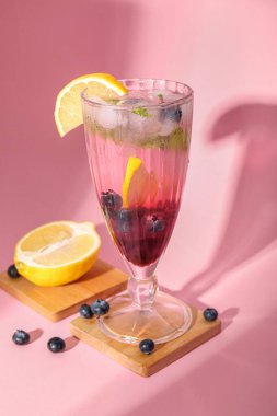 Pembe arka planda bir bardak taze yabanmersini limonatası.