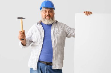 Gri arka planda boş poster ve çekiçle son sınıf öğrencisinin portresi. İşçi Bayramı kutlamaları