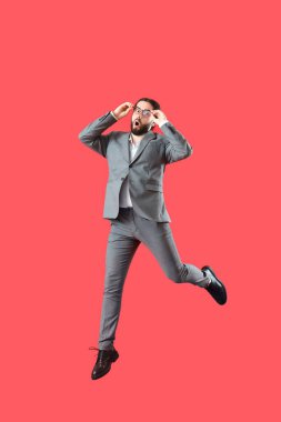 Kırmızı arka planda atlayan şaşkın iş adamı