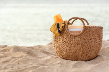 Okyanus kıyısında tatil köyünde kumsalda farklı plaj aksesuarlarıyla dolu bir çöp torbası.