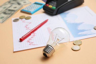 Ampul, bozuk paralar ve çizelgeler bej arka planda, yakın plan. Ev kirası kavramı