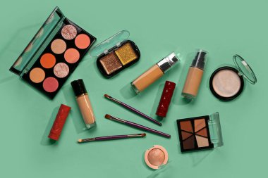 Güzel göz falı paletleri ve yeşil arka planda farklı dekoratif kozmetikler.